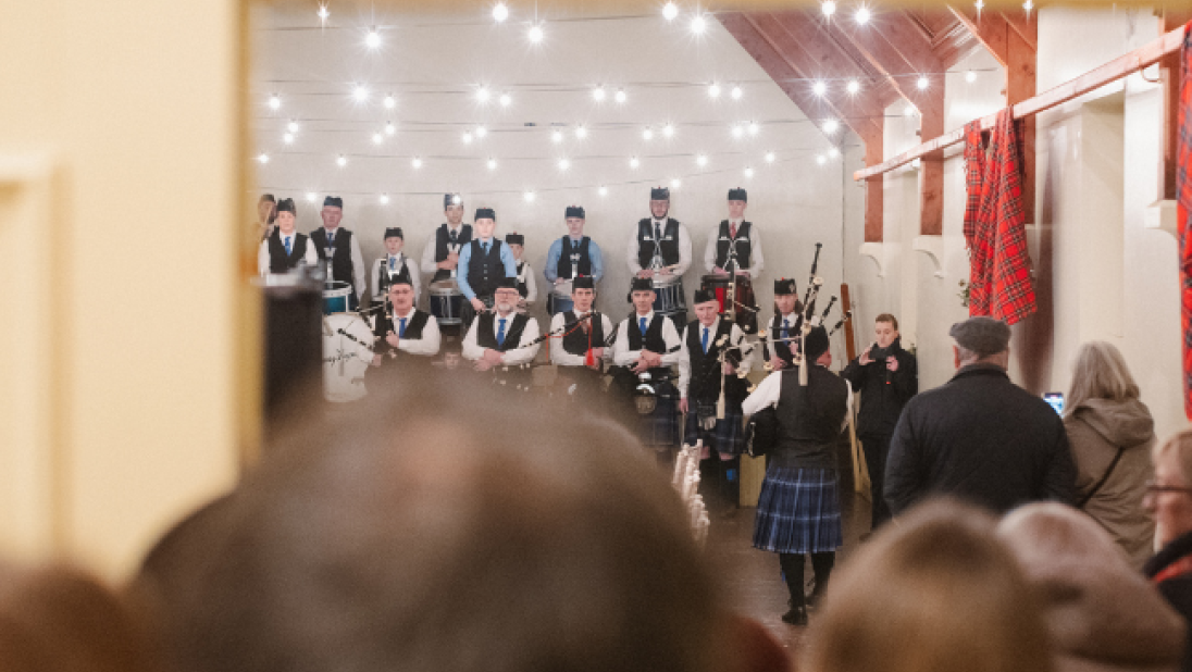 a crowd looking in the door of a room to see the ferguson pipe band