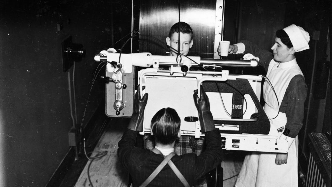 A nurse assists a doctor in demonstrating an x-ray machine.