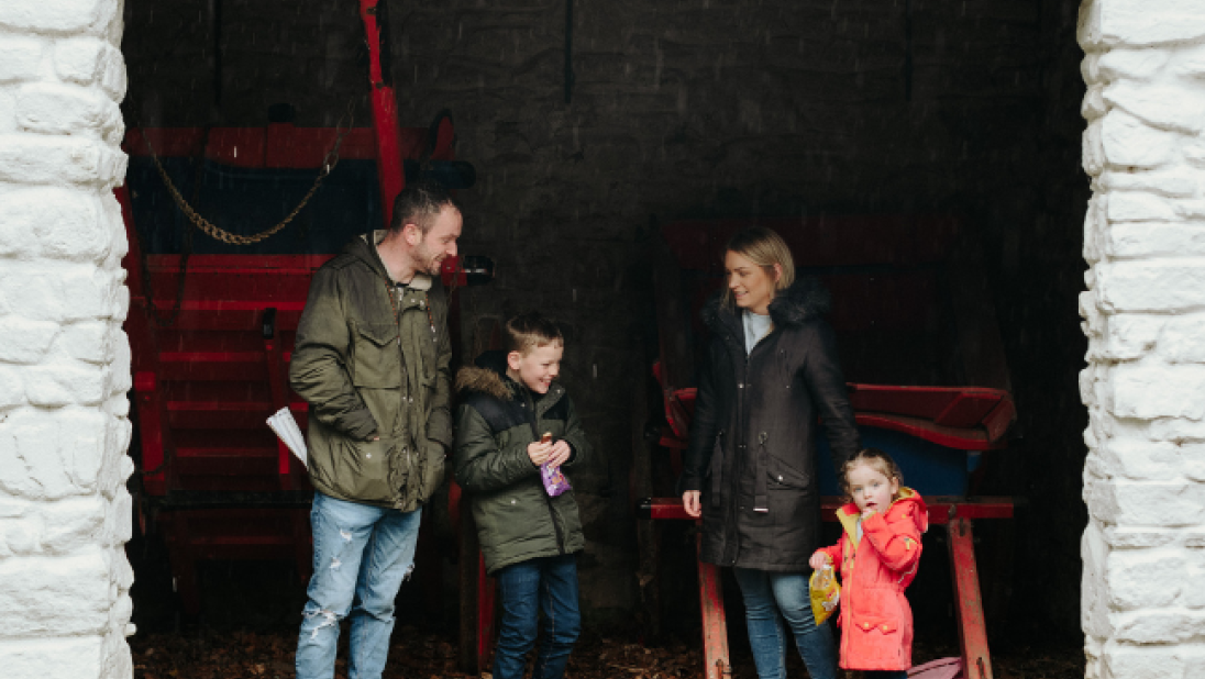 A family of four in front of a building at the folk park - a man, a young boy, a woman and a young girl