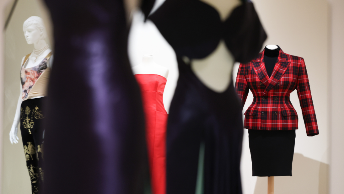 Colourful garments on white mannequins in a cream painted room.
