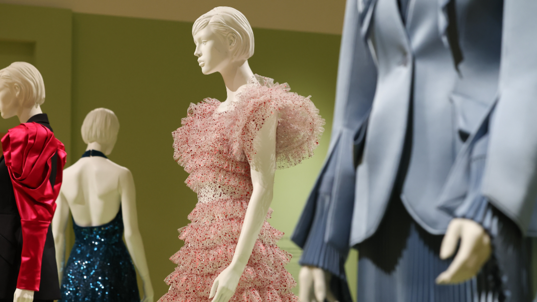 Colourful garments on white mannequins in a mint green painted room