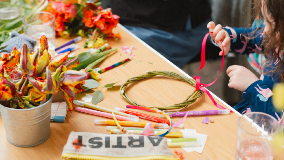 A child making a flower crown at a brown table