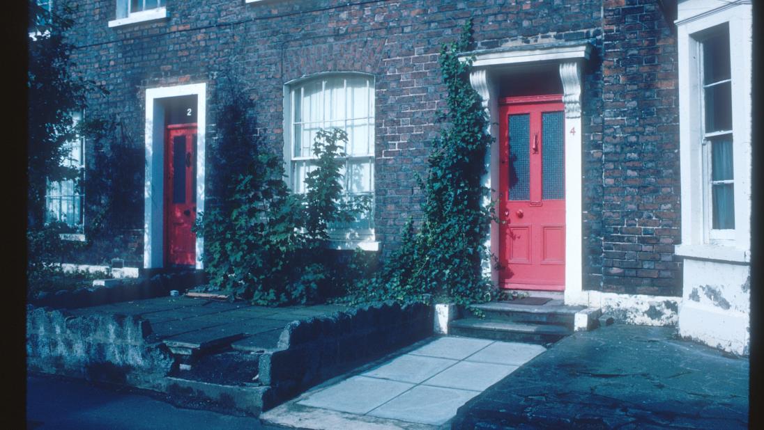 A colour image of a the facade of a building in south Belfast. The front door is red.