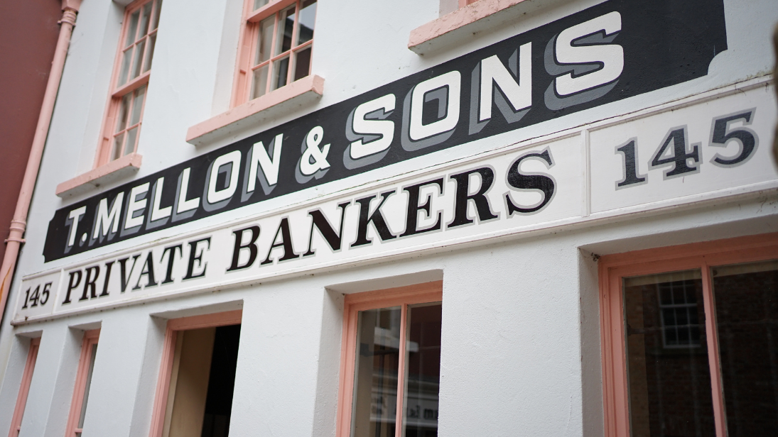 An image of the sign above the Mellon Bank, reading T. Mellon & Sons, Private Bankers.