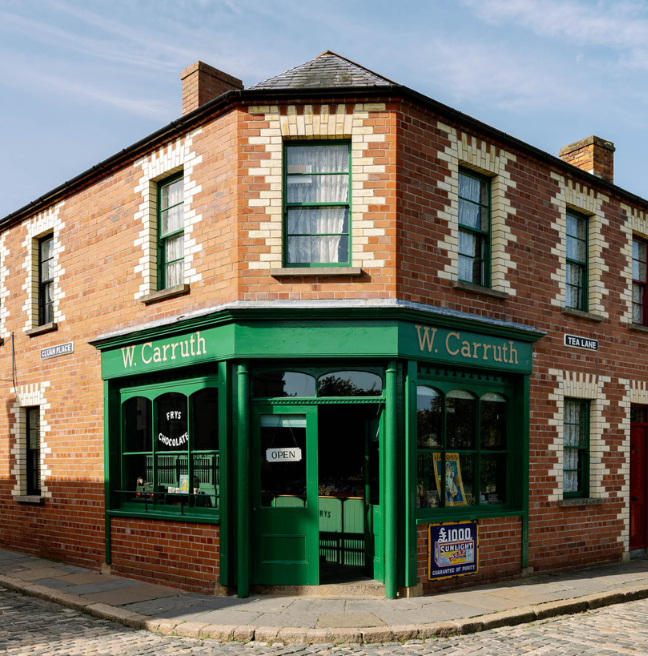 A green corner shop sits on the corner of a red-brick building.