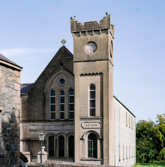 A large hall with a tower and a crucifix on the roof.