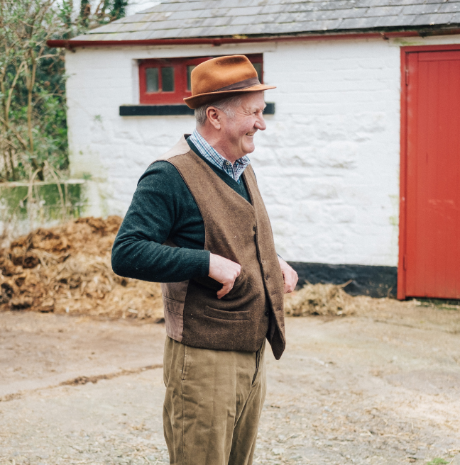 A man who is a farmer standing outside a farmhouse in ulster folk museum