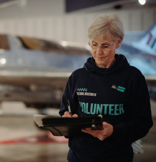A female volunteer at the transport museum using a clip board to write