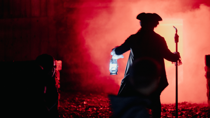 A man dressed in costume holding a torchlight