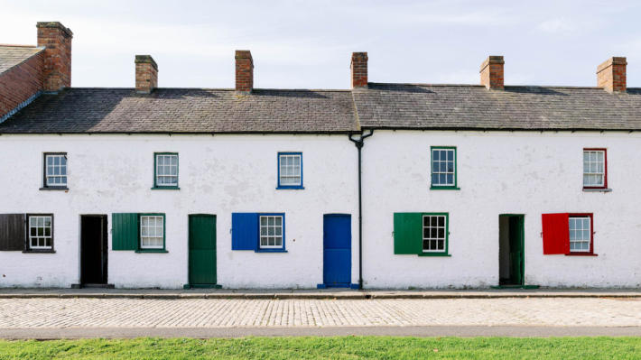 A whitewashed row of houses with brightly coloured doors and windows.