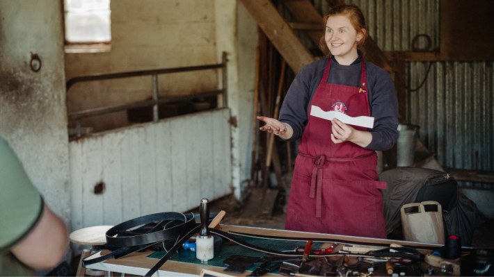 A lady talking to a visitor about leatherwork