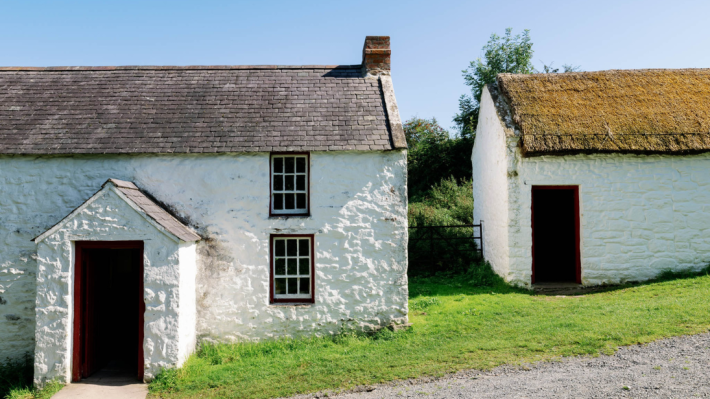 A white house with a slate roof, on a sunny hill.