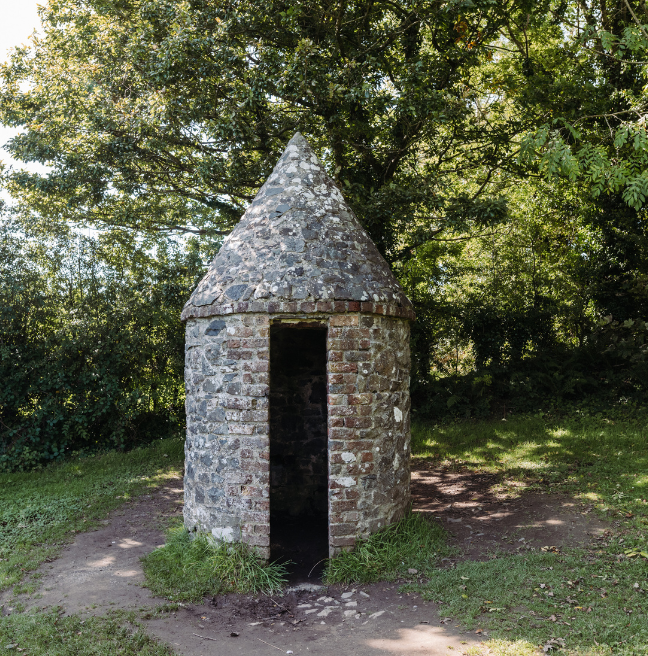 A small stone tower with no door sits in a field.