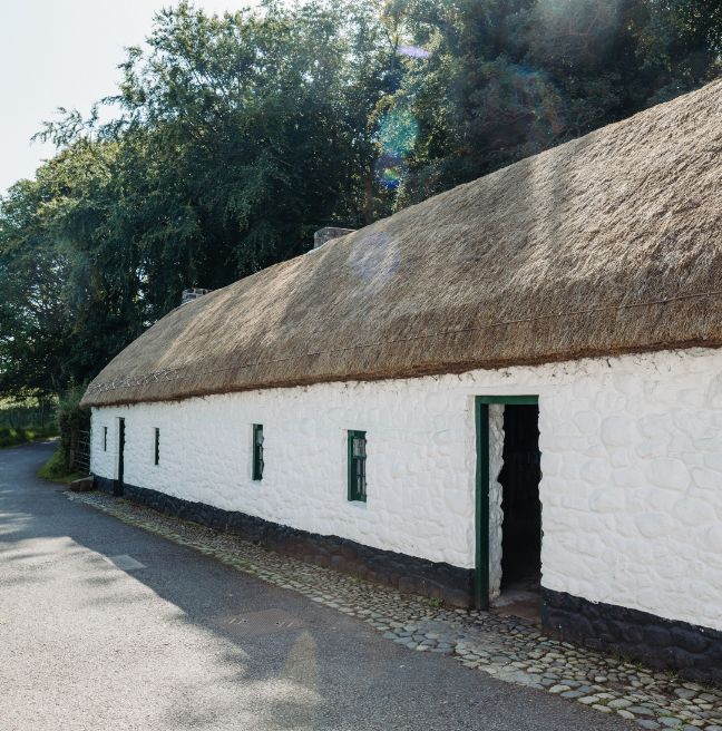 A long cottage with two doors and a thatched roof. 