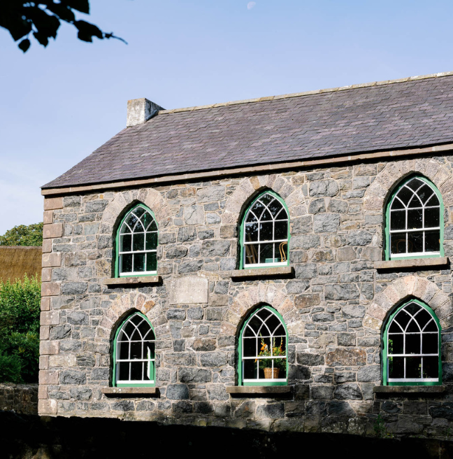 A grey school building with six ornate green windows.