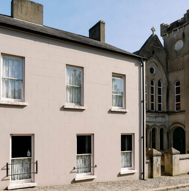 A house in the foreground, with a parochial hall in the background.