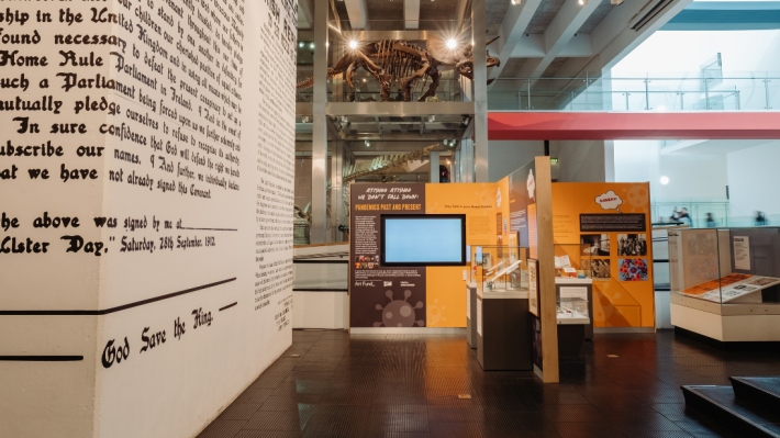 Modern history gallery at Ulster museum, text printed onto walls with a grey and orange section in the middle of the floor focusing on the pandemic history