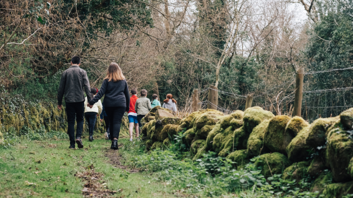 A couple walking in nature at the ulster folk museum with several children 