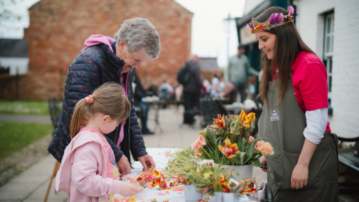 A lady and a child looking at flowers with a lady in a flower crown 