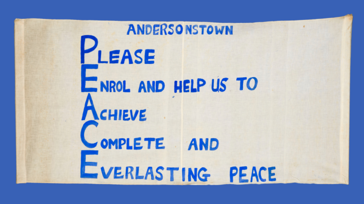 A banner from a peace march that reads, 'Andersonstown, Please Enrol and help us to Achieve Complete and Everlasting Peace'.