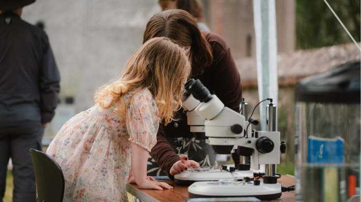 A blonde girl looking into a microscope