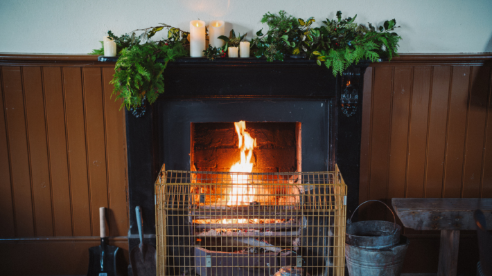 An open, lit fire with seasonal decor and candles sitting on top
