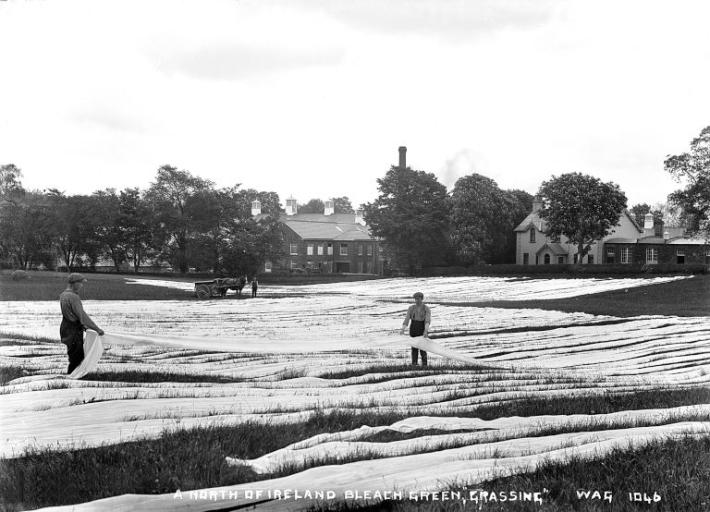 Two men laying out linen to dry on the grass on the "bleach green"
