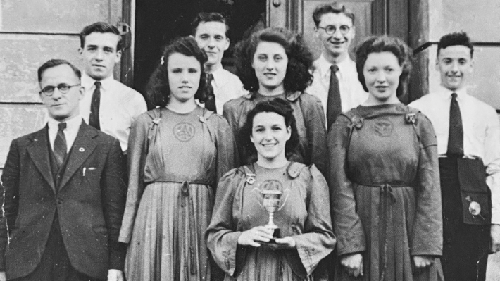 9 men and woman standing on steps - a black and white image
