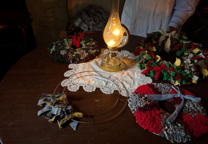 A table with a variety of rag wreaths on top, surrounding a candle.