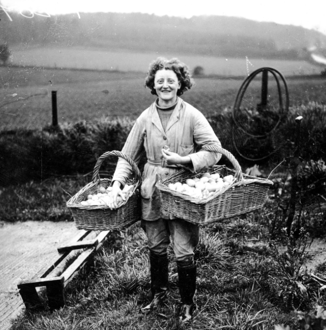 A woman carrying two baskets of eggs