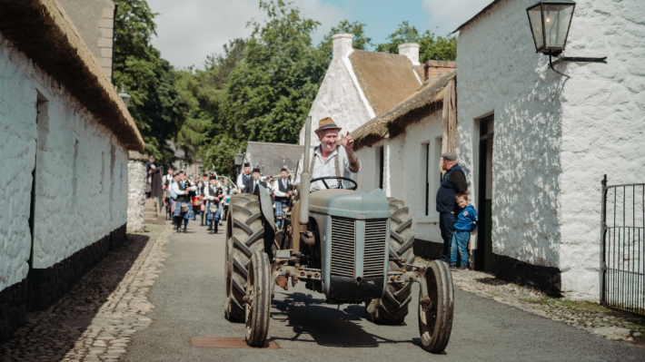 A man on a tractor driving through  the ulster folk museum 