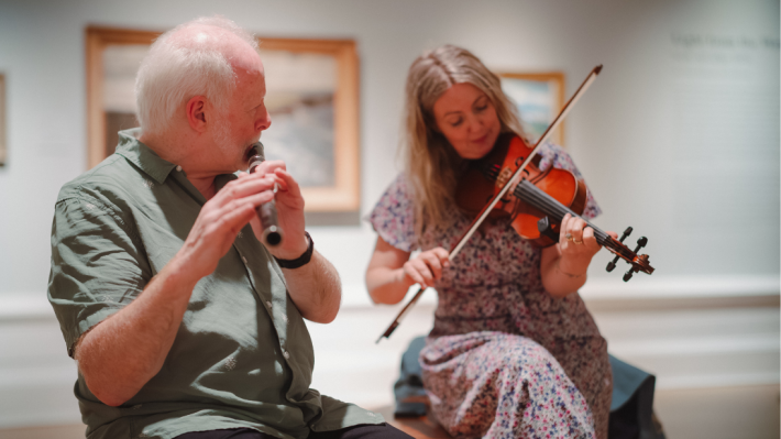 A man and a woman playing instruments - a flute and a violin 