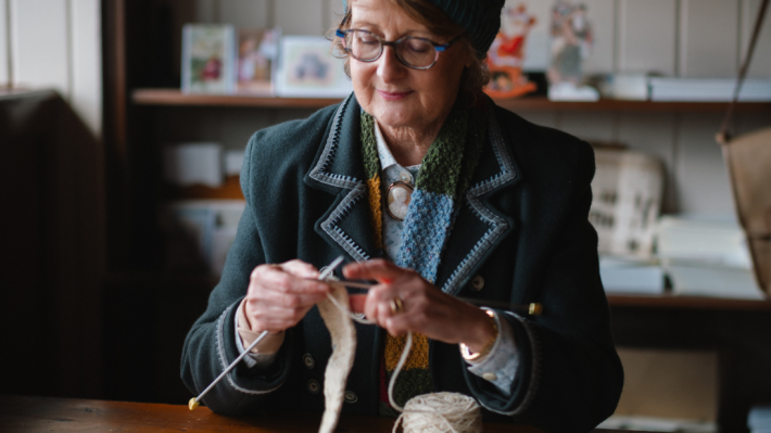 A lady dressed in costume knitting at a desk