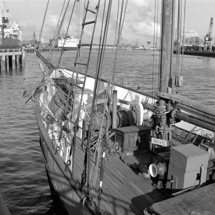 Black and white photograph, looking closely at the deck of the Result. Private sign hanging from the mast