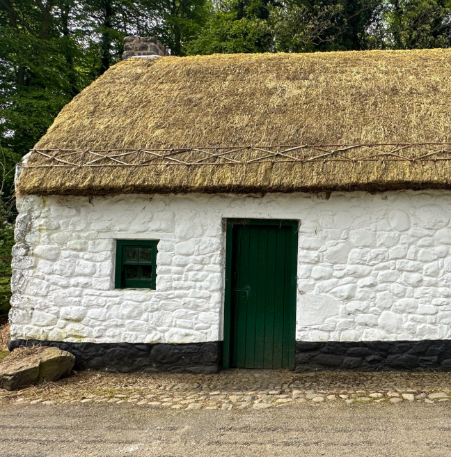 An image of a whitewashed cottage with a newly thatched roof.