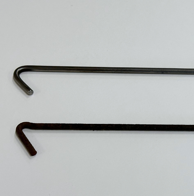 The ends of two thatching needles; one is silver and new, the other is older and more worn and rusted.