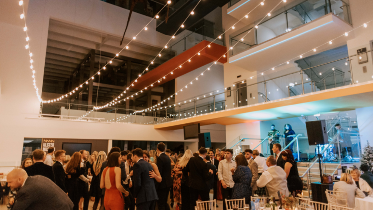 A dancefloor packed with festive party goers at the Ulster Museum, singers on steps and festoon lights hang above the dancefloor