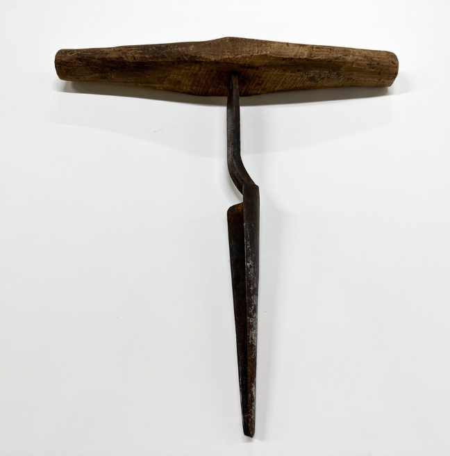 A carpenter's auger, with a wooden handle and a perpendicular metal tool.