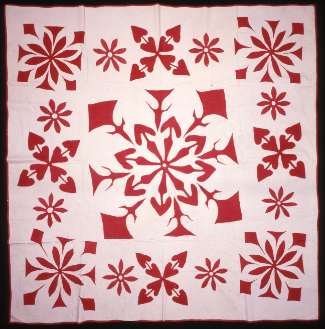 A white and red quilt with patterns like snowflakes on it.