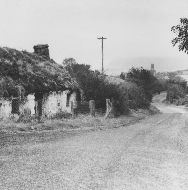 A photo of an old, almost run down house by the side of a road.