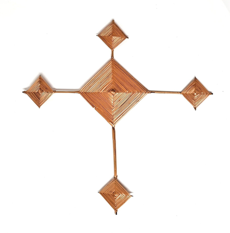 A Saint Brigid's Cross. The cross is shaped like a crucifix, with a diamond centre and four diamond shapes at the end of thin legs emanating from the centre.