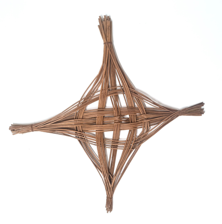 A Saint Brigid's Cross. The cross is unusally shaped, with two main bundles of rushes intricately woven together.