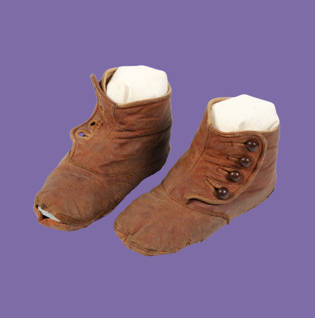 Old pair of brown leather children's boots on a purple background