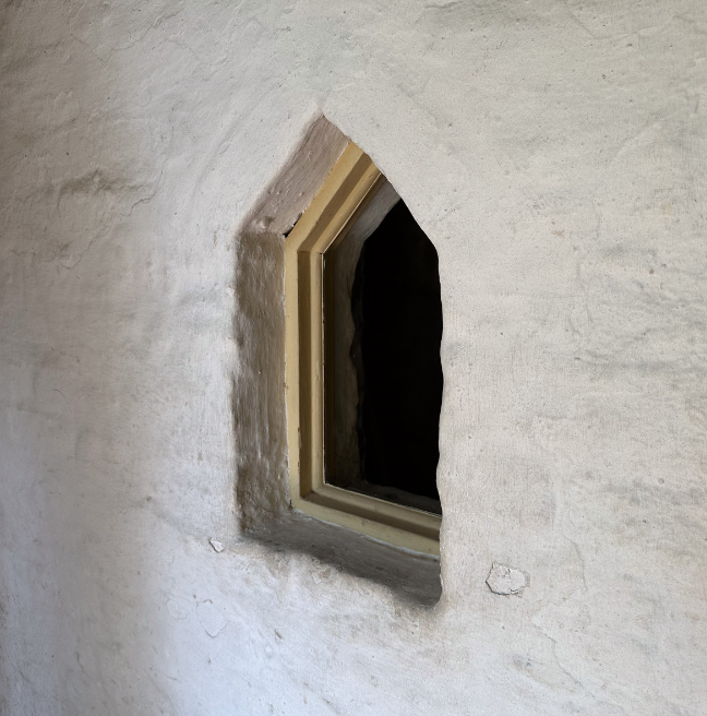 A close up of a small window in a jamb wall.