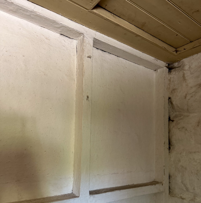 The wall of a room, made out of wood, showing its distinctly DIY construction.