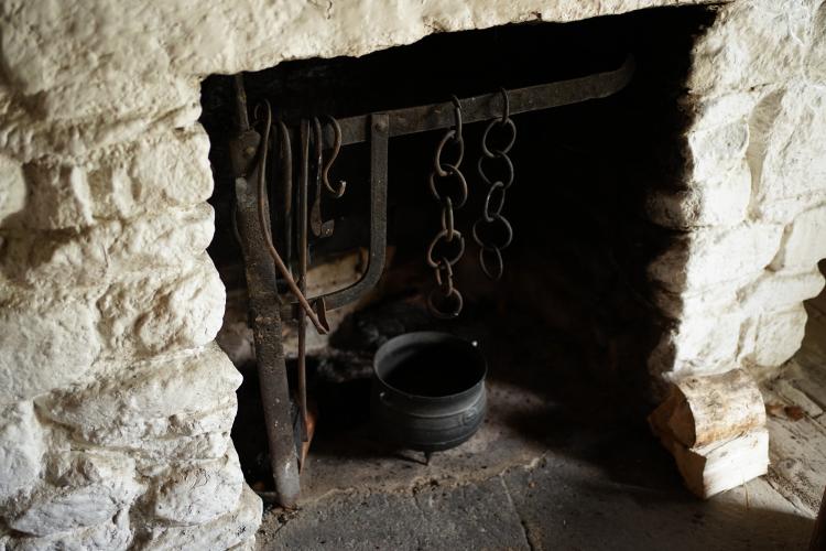 A stone fireplace with an iron pot nestled inside.