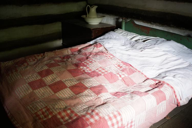 A bed with a traditional patchwork quilt on top.