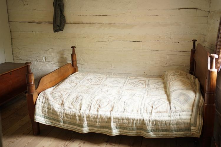 A bed on a wooden frame with a tradtional quilt on top.