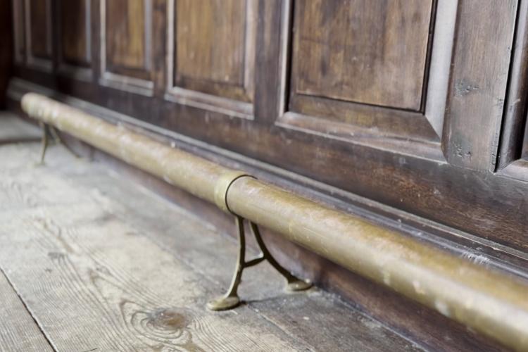 An image of a foot rest on the floor of a bank. It is a brassy colour and runs the length of the counter.