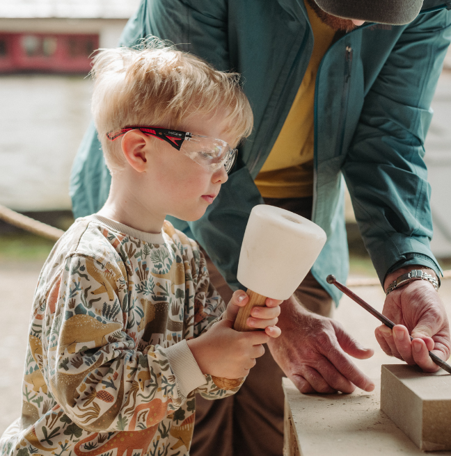 a boy holding a white tool and wearing goggles 